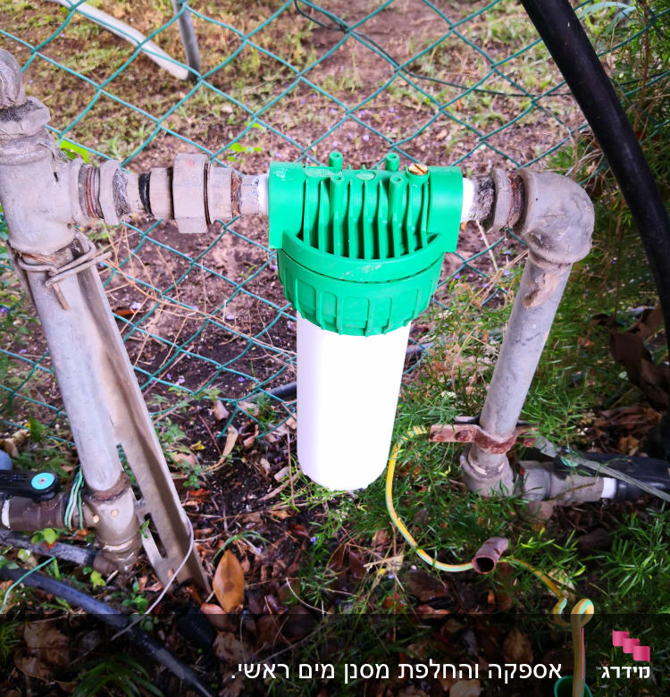 מסנן מים ירוק ולבן מחובר לצינורות מתכת